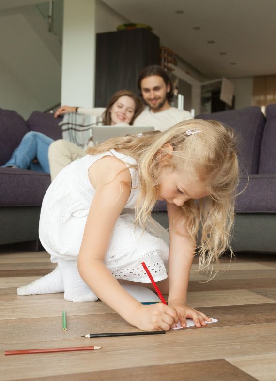 Davofrío - Expertos en Instalación y Mantenimiento de Suelo Radiante en Alicante, Valencia y Murcia - Niña pintando en un papel en un suelo radiante con su familia